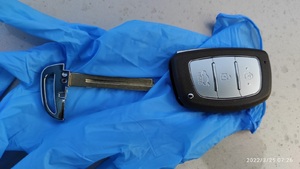 Łamak i kluczyk urządzenie do uruchomienia auta oraz kluczyki leżą na niebieskim tle