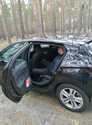 zatrzymany Mołdawianin siedzi skuty kajdankami na tylnym siedzeniu granatowego auta