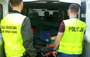 1 218 sztuk podrabianej odzieży zatrzymano w Krotoszynie Funkcjonariusz SG i policji stoją przy tylnych drzwiach wyładowanego podrobionymi ubraniami dostawczaka