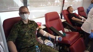 Na straży życia - akcja honorowego oddawania krwi na fotelu w autobusie siedzi funkcjonariusz Straży Granicznej w mundurze polowym i oddaje krew