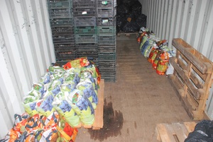 Miejsce za paletami wypełnione było nielegalnym towarem na pierwszym planie różnokolorowe worki a za nimi ukryty w czarnych workach tytoń