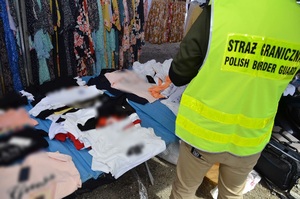 Podrobione ubrania na stoisku w Bielawie Podrobione ubrania na stoisku w Bielawie obok stoi funkcjonariusz Straży Granicznej w kamizelce odblaskowej