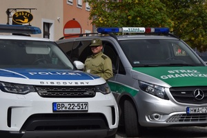Funkcjonariusz Nadodrzańskiego Oddziału Straży Granicznej na tle samochodów służbowych, uczestniczący we wspólnym polsko-niemieckim patrolu Funkcjonariusz Nadodrzańskiego Oddziału Straży Granicznej na tle samochodów służbowych, uczestniczący we wspólnym polsko-niemieckim patrolu